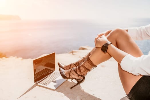 Happy girl doing yoga with laptop working at the beach. beautiful and calm business woman sitting with a laptop in a summer cafe in the lotus position meditating and relaxing. freelance girl remote work beach paradise