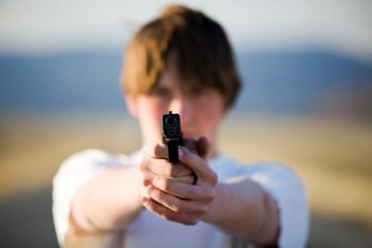teenager pointing handgun at camera
