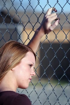 teen girl looking through fence