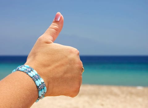 Thumbs up hand sign isolated on beach
