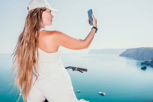 A woman cyclist on a mountain bike looking at the landscape of mountains and sea. Rear view of cyclist woman standing in front to the sea with outstretched arms. Freedom and healthy lifestyle concept