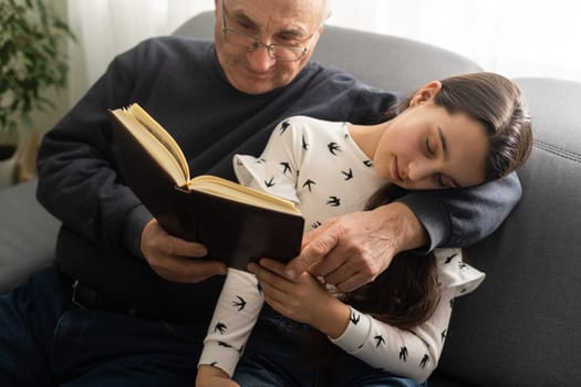 Book, family and children with a girl reading to her grandfather on the floor of their living at home. Kids, read and story with a senior man and granddaughter bonding in their house during a visit