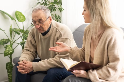 Mature man at a session with a psychologist. The doctor listens and writes. Help with depression, psychiatric diagnosis