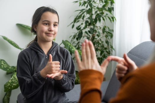 daughter talk with middle aged mother people using sign language, family sitting on armchair side view, teacher teach teenager deaf-mute girl to visual-manual gestures symbols concept image.