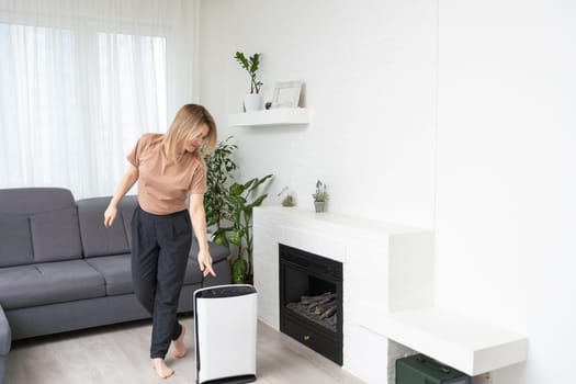 Woman using air purifier, dust filter, clean and health air.