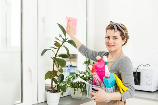 Beautiful woman cleaning window at home