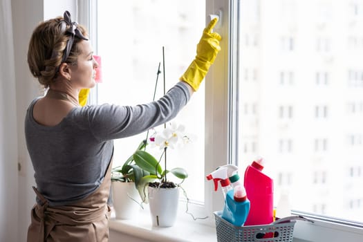 Woman cleaning and polishing the kitchen worktop with a spray detergent, housekeeping and hygiene concept