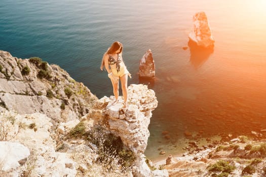 Woman travel sea. Happy tourist taking picture outdoors for memories. Woman traveler looks at the edge of the cliff on the sea bay of mountains, sharing travel adventure journey.