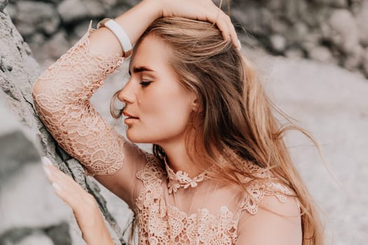 Woman travel sea. Young Happy woman in a long red dress posing on a beach near the sea on background of volcanic rocks, like in Iceland, sharing travel adventure journey