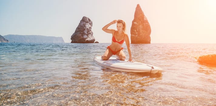 Close up shot of beautiful young caucasian woman with black hair and freckles looking at camera and smiling. Cute woman portrait in a pink bikini posing on a volcanic rock high above the sea