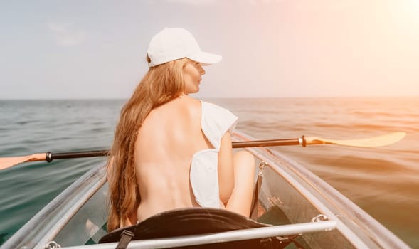 Woman in kayak back view. Happy young woman with long hair floating in transparent kayak on the crystal clear sea. Summer holiday vacation and cheerful female people having fun on the boat.