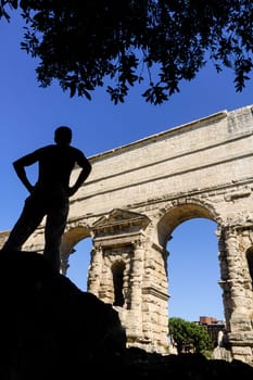 Silhouette of seated traveler admiring the Porta Maggiore, in Rome. Vertical view