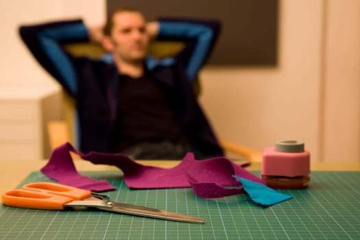 Man with relaxed posture and scissors in foreground