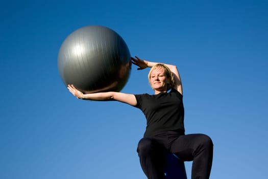 Woman with ball doing sports exercises