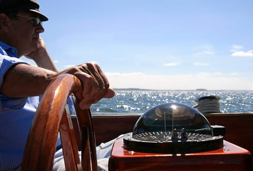 Sailing in old age,pensioner at the helm/steering wheel of his sailboat