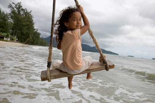 Child on swing by the sea