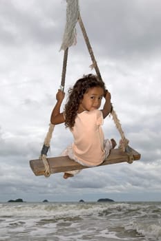 Girl on swing by the sea