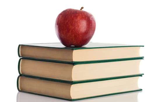 A red apple on top of three books