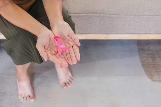 Close-up woman hand holding pink ribbon symbol. Breast cancer awareness and october pink day, world cancer day, national cancer survivor day. healthcare concept.