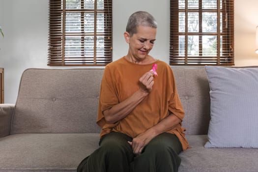 Close-up elderly senior woman with pink ribbon at her home. Health care, support, prevention. Breast cancer awareness month concept.