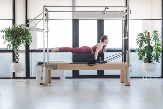 Woman doing pilates exercise on cadillac reformer machine