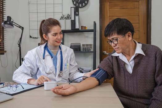 A nurse visits an elderly person for a health check. A young nurse measures the blood pressure of an elderly man at home. Happy elderly Asian man in his 60s measuring blood pressure in his home..