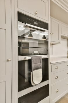 a kitchen with white cupboards and an oven in the middle one has a towel hanging on it's rack