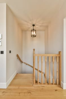 an empty room with wooden stairs and a light fixture on the left side of the room, there is a white wall in the