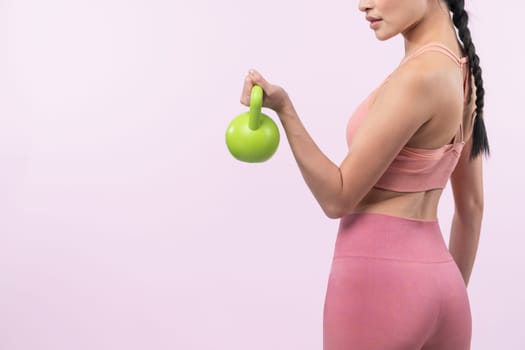 Vigorous energetic woman doing kettlebell weight lifting exercise on isolated background. Young athletic asian woman strength and endurance training session as body workout routine.