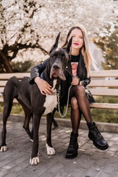 A woman walks with her Great Dane in an urban setting, enjoying the outdoors and the company of her dog