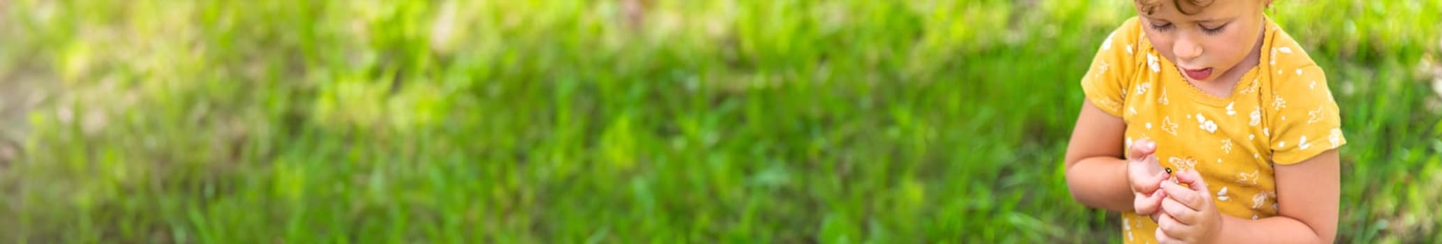 A child holds a ladybug on her hand. Selective focus. Nature.