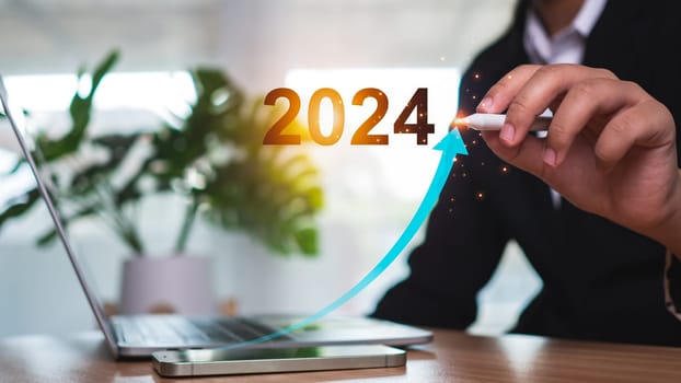 Stock trading. Finance. Investing. Growing business. Businesswoman in suit pointing with a pen at the tip of an arrow and a graph bar Represents business growth in 2024.
