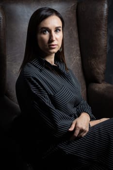 a young brunette female artist stands behind an easel. photo shoot on a black background in the studio