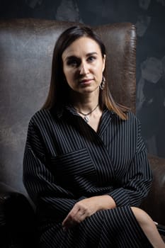 a young brunette female artist stands behind an easel. photo shoot on a black background in the studio