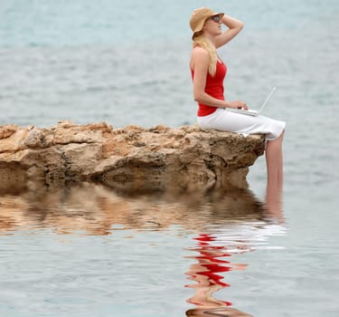 Woman using laptop by the sea