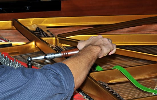 The tuning hammer is used to adjust the strings of a concert grand piano.
