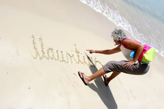 Woman writes Mauritius in the sand