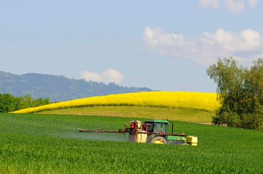 Tractor with trailed sprayer spraying a field