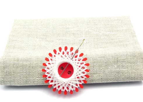 White thread with needle on linen