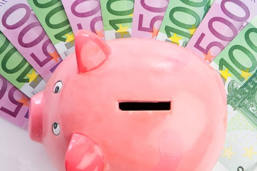 Pink piggy-bank over many notes