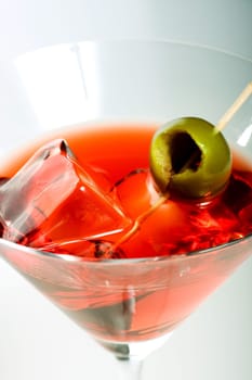 Martini glass with olive and ice cube