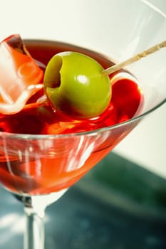 Martini glass with olive and ice cube