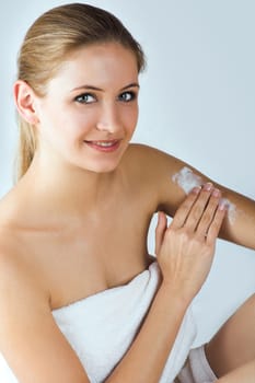 Young woman applying cream with body lotion