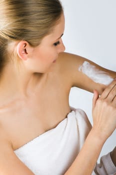 Young woman applying cream with body lotion
