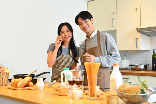 Beautiful young couple standing at worktop in the kitchen preparing and preparing breakfast together..