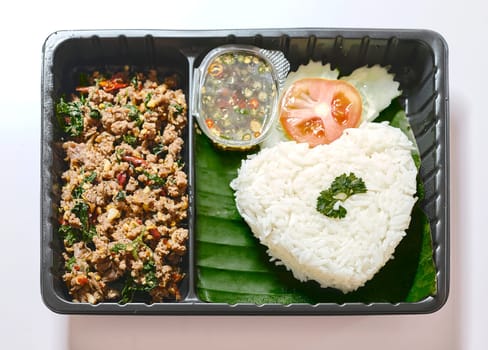 Basil fried rice with pork in plastic box at street market , fast food in Thailand, Thailand's national dishes, Thai name is Pad kra prao Mou,famous food in Thailand