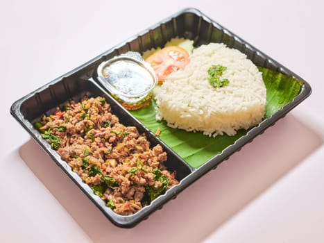 Basil fried rice with pork in plastic box at street market , fast food in Thailand, Thailand's national dishes, Thai name is Pad kra prao Mou,famous food in Thailand