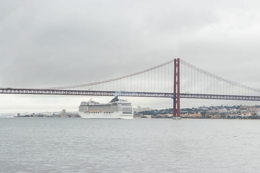 Huge cruise ship passes along the river under the bridge in cloudy weather. Mid shot