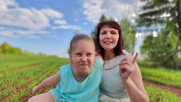 Happy mother and daughter enjoying rest, playing and fun on nature in green field. Woman and girl resting outdoors in summer or spring day