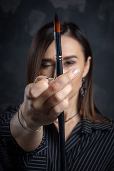 Portrait of a female artist, with brushes in her hands.
 Photo shoot on a black background in the studio